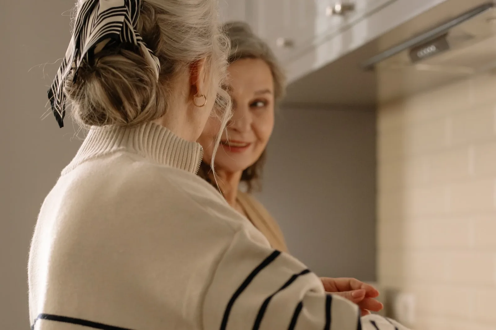 Caregiver and older woman smiling together in front of a mirror