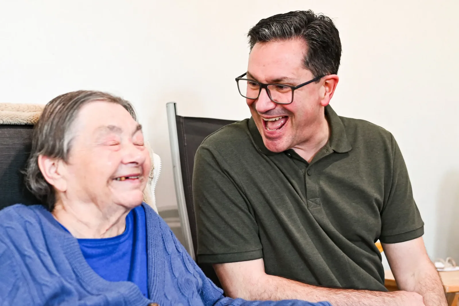 Older woman laughing with a family caregiver at home