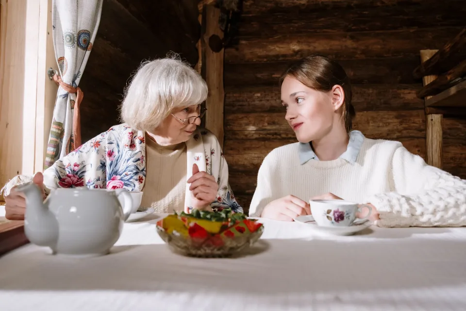 Caregiver and older woman sharing tea and conversation at home