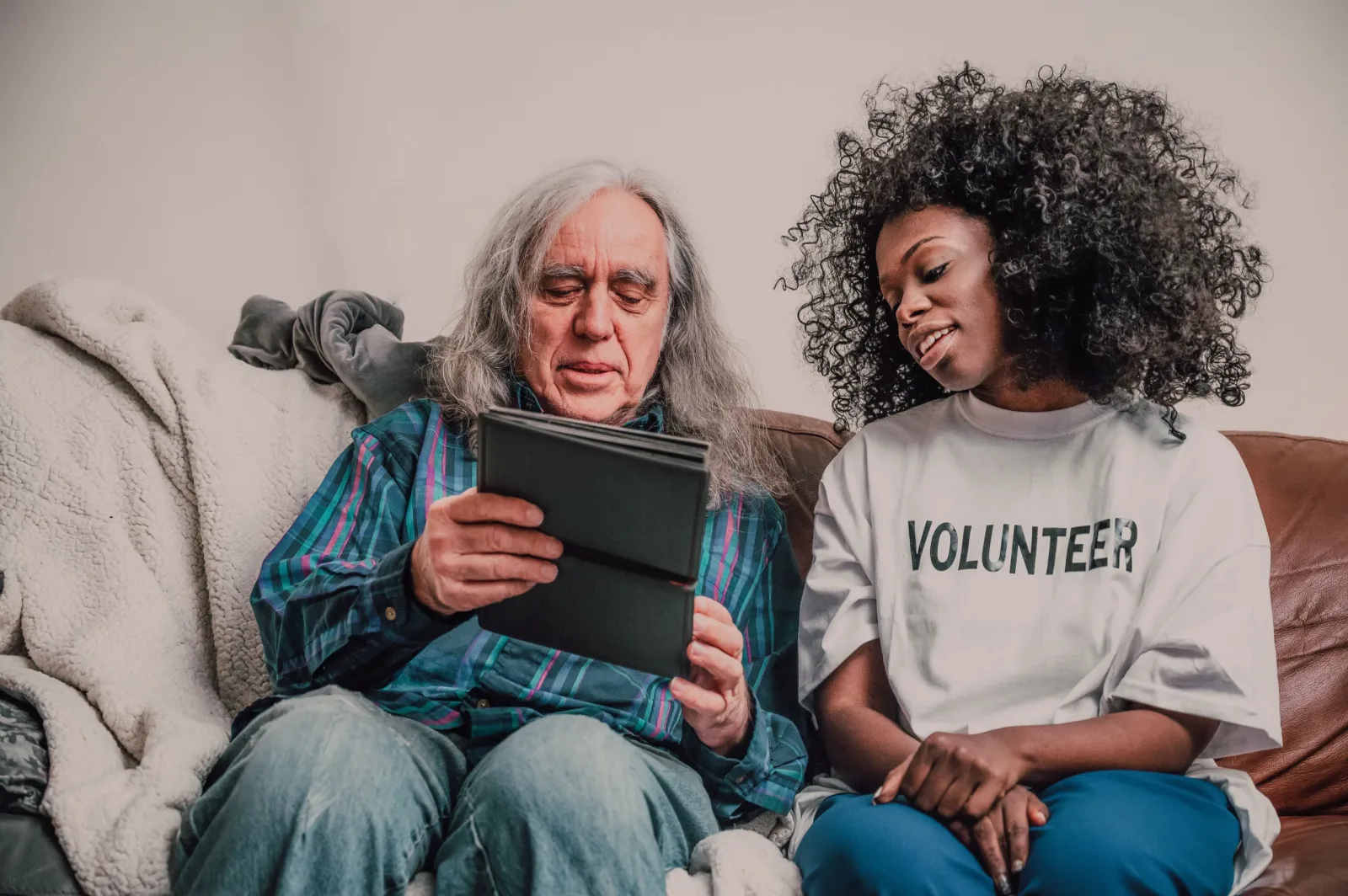 Volunteer helping an older man use a tablet at home