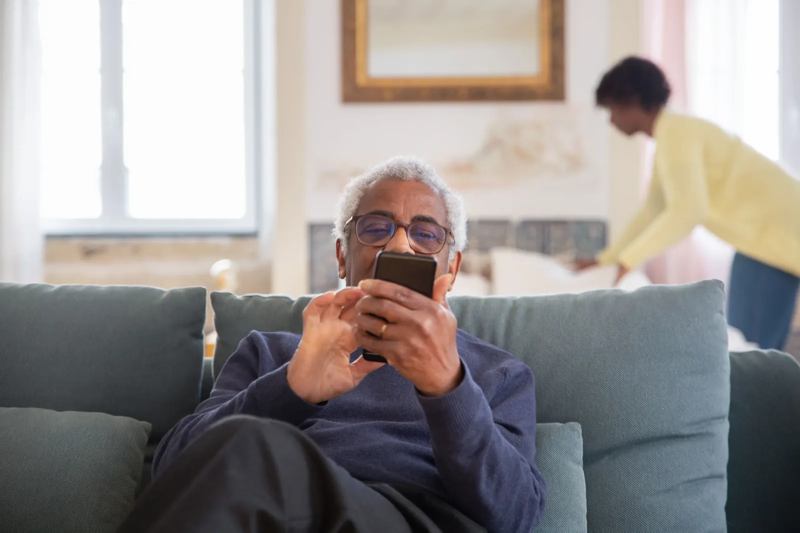 Older woman using a smartphone while relaxing on a sofa