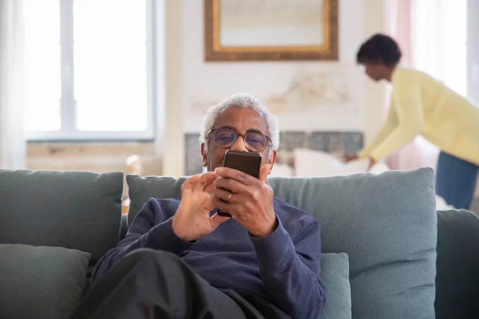 Older woman using a smartphone while relaxing on a sofa