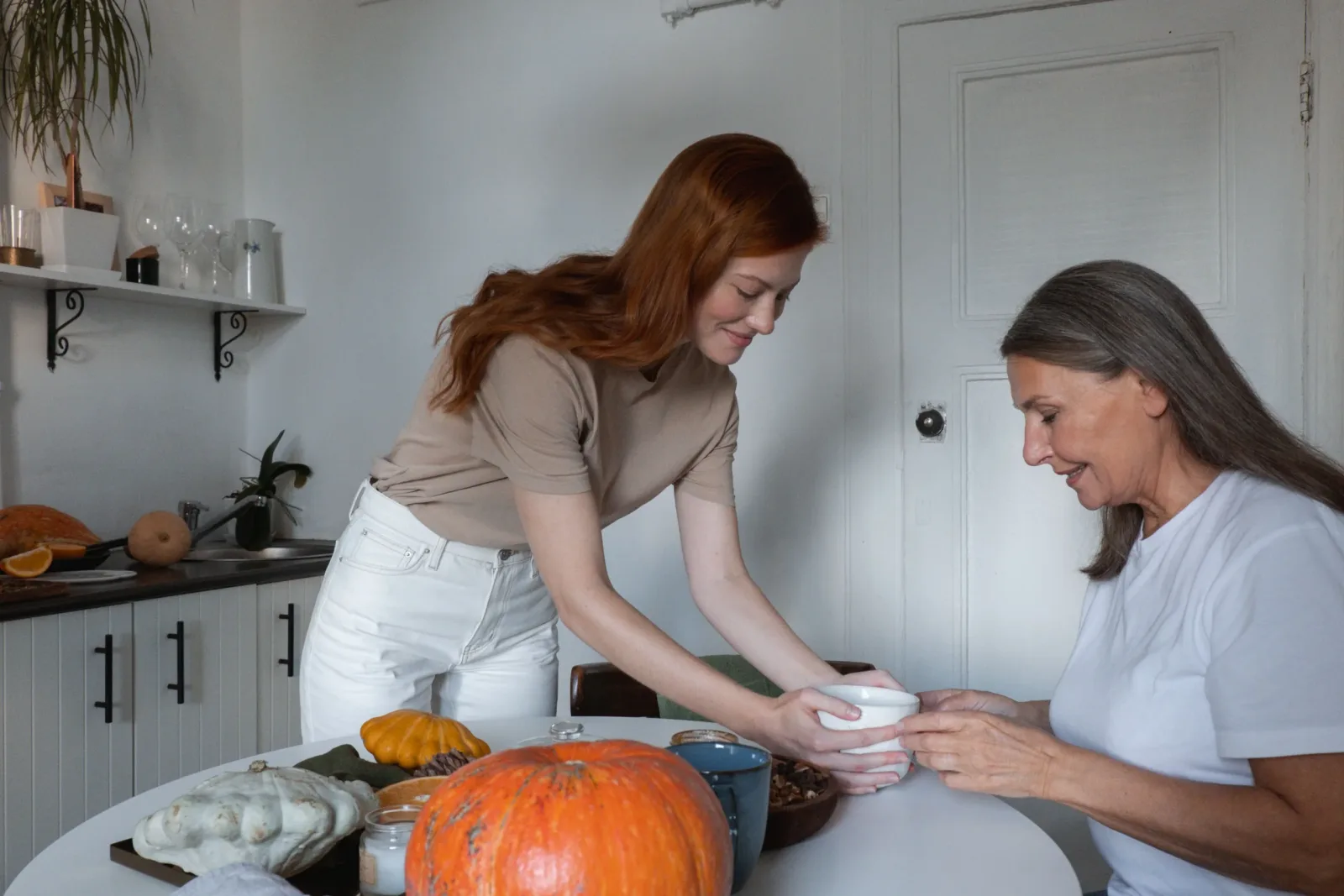 Caregiver and older woman baking together at a kitchen table