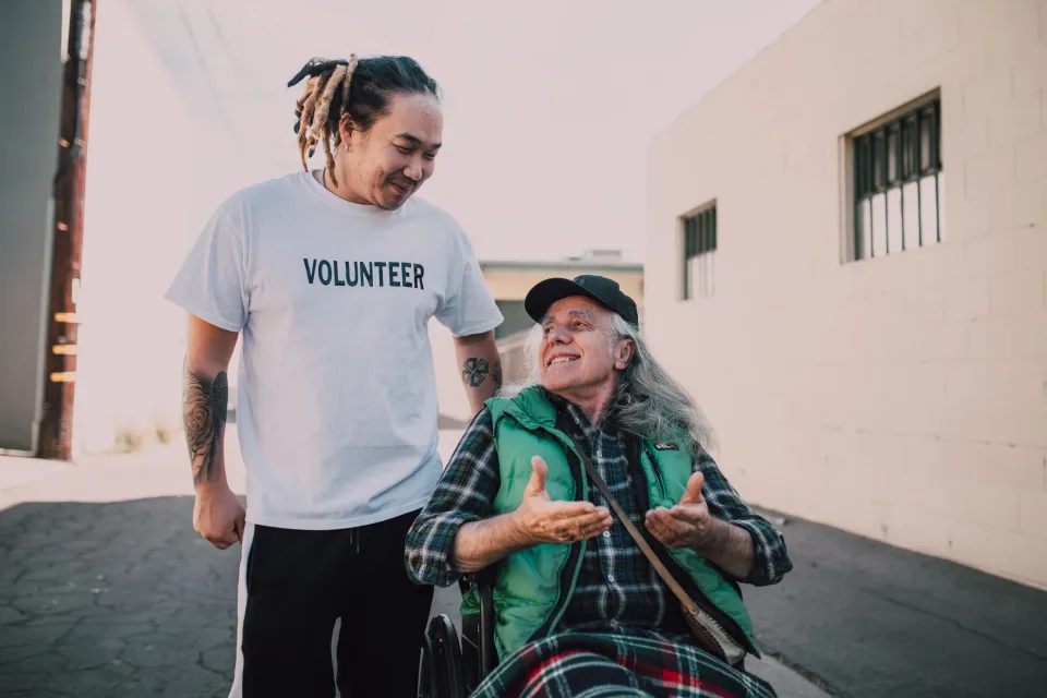Volunteer talking with an older wheelchair user outdoors