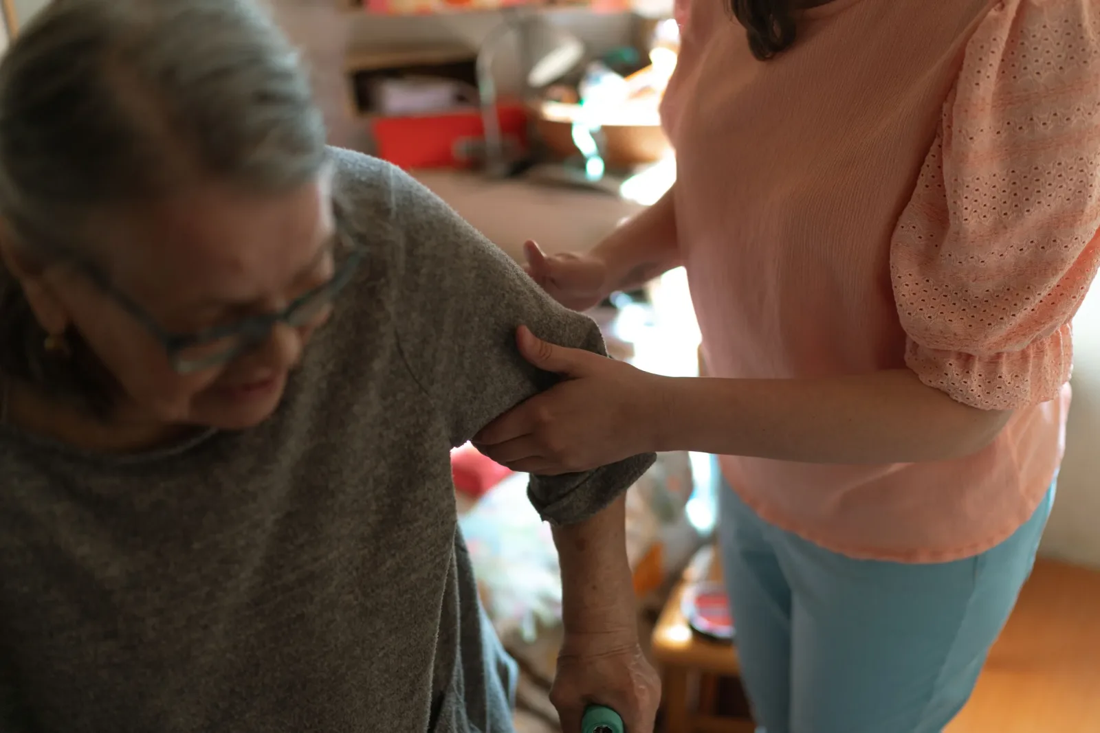 Caregiver helping an older woman stand and move safely at home