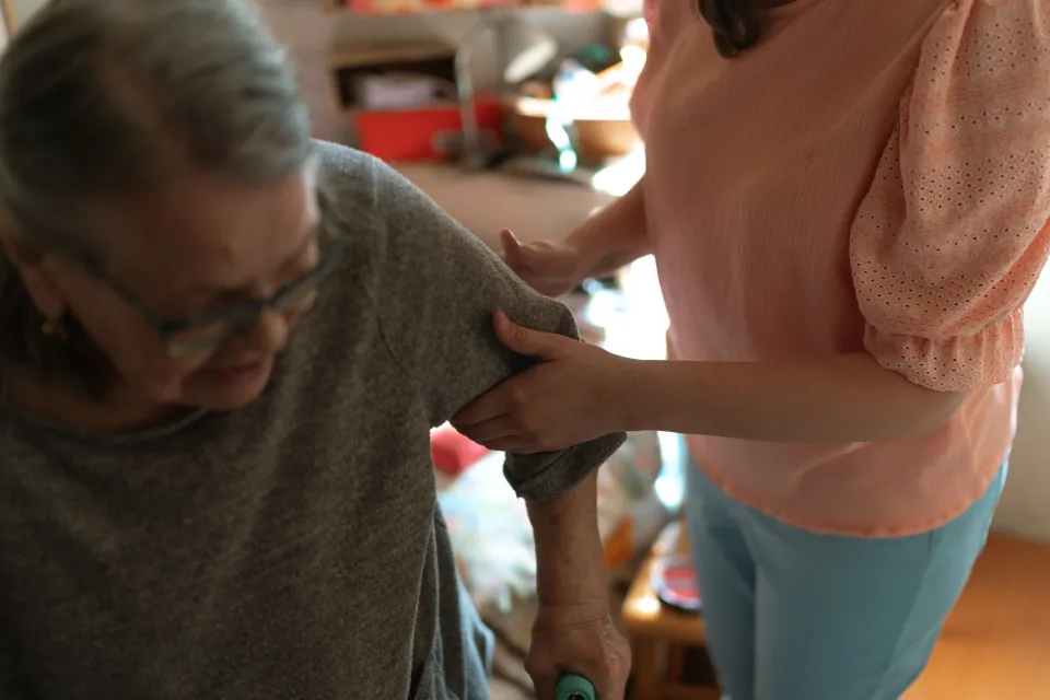 Caregiver helping an older woman stand and move safely at home