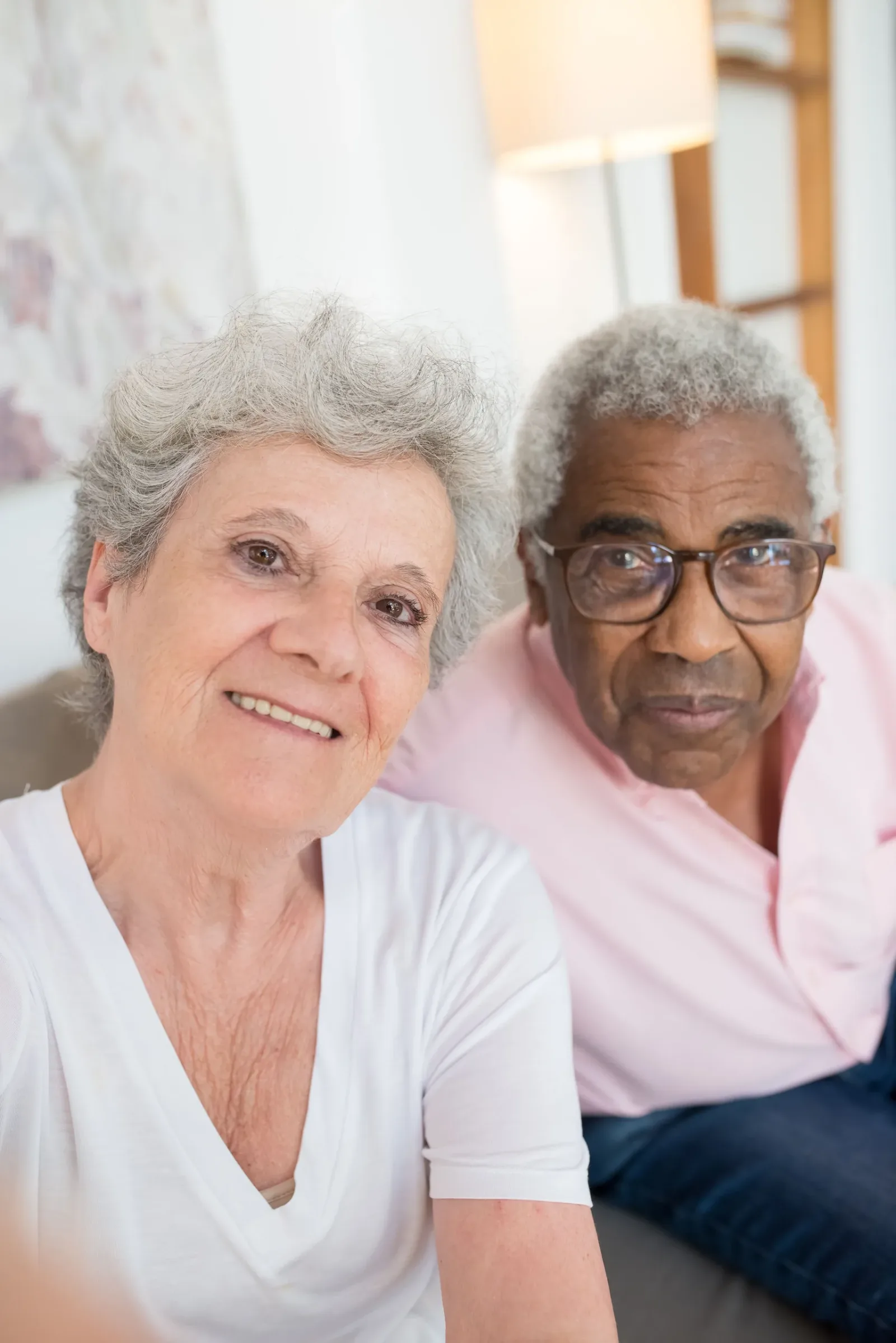 Two older women smiling together for a portrait at home