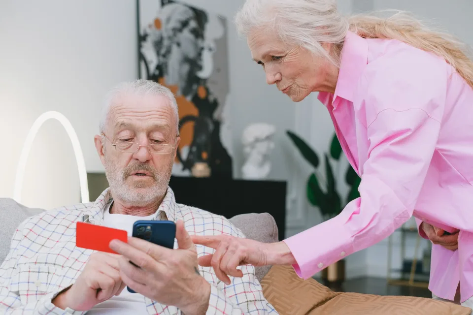 Older couple using a smartphone and payment card together at home