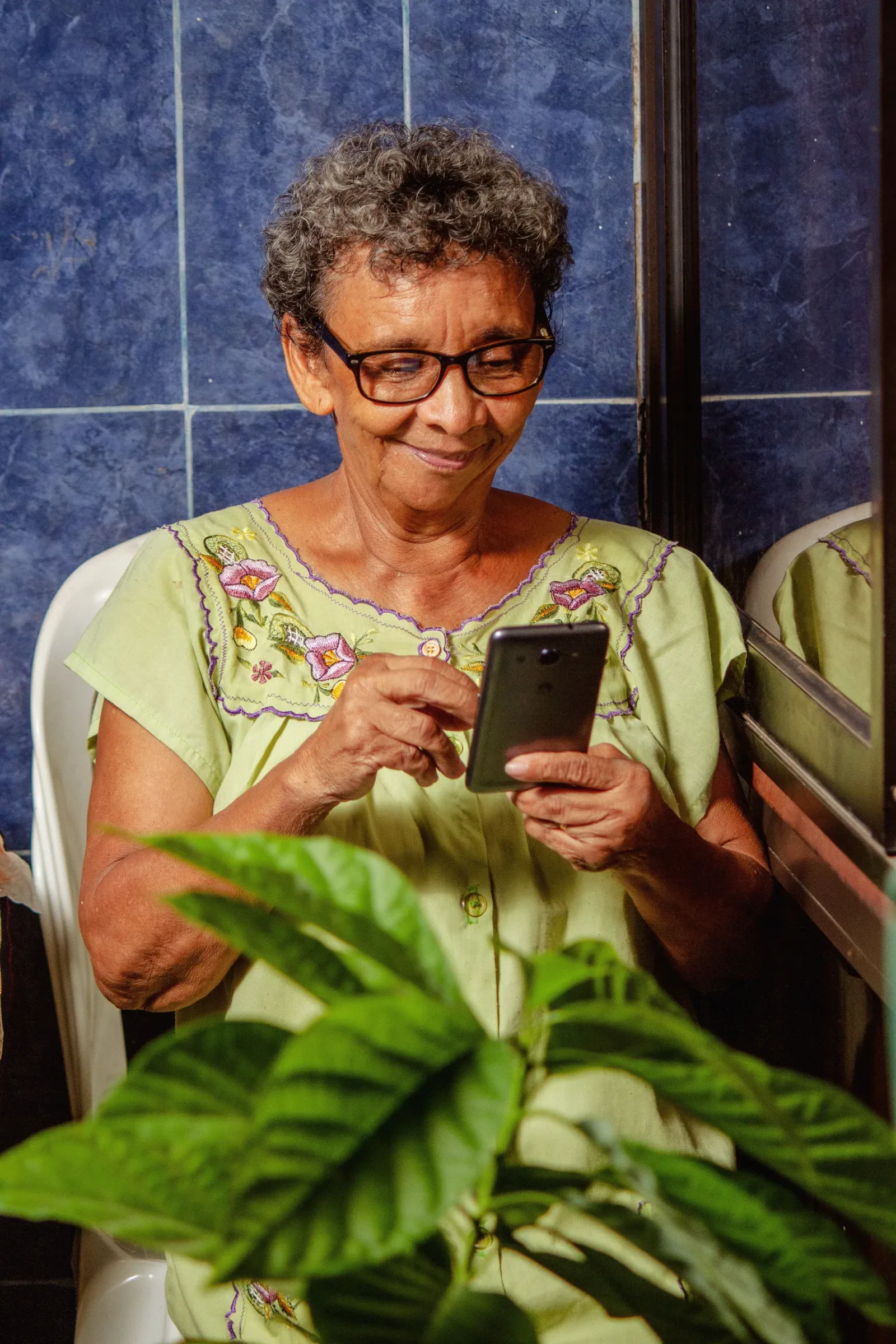 Older woman smiling while using a smartphone at home