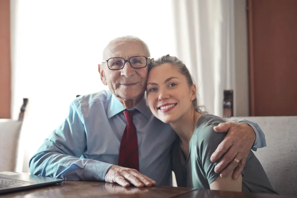 Older man and younger companion smiling together at a table