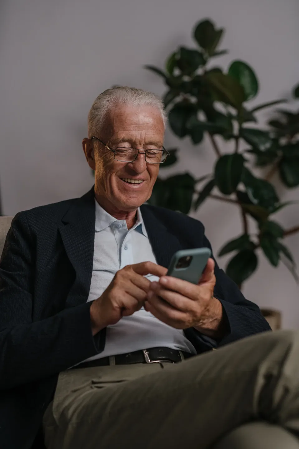 Older man smiling while using a smartphone at home