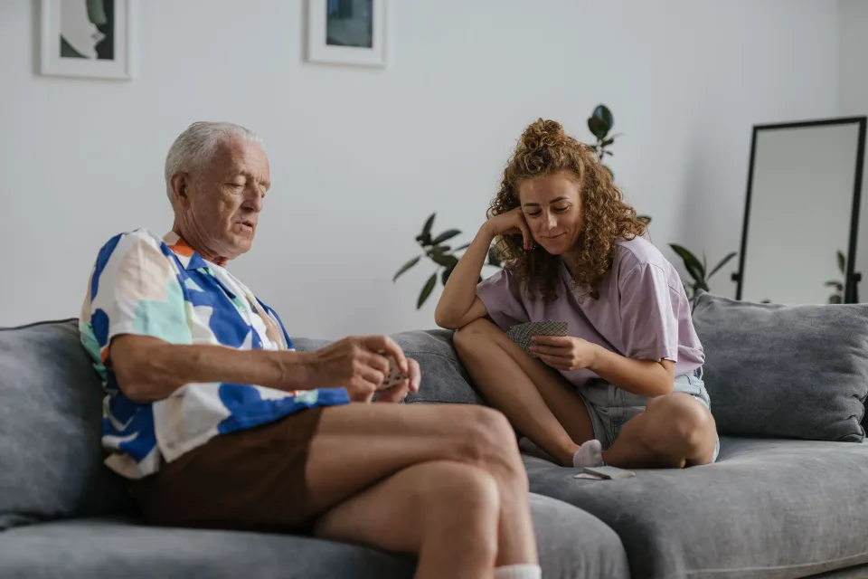 Older man talking with a caregiver while seated on a sofa